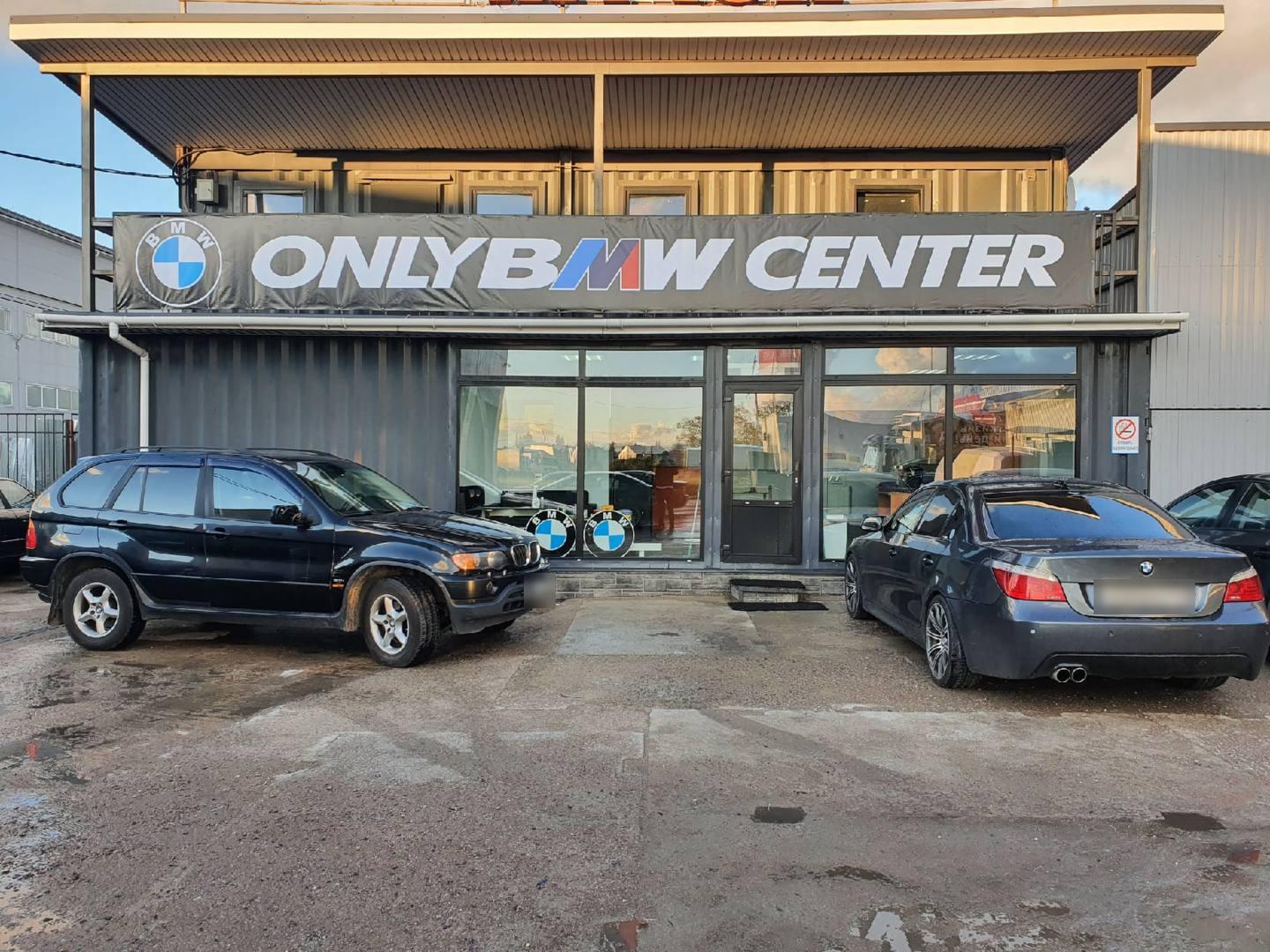 Фасад здания с вывеской ONLY BMW CENTER, перед ним BMW X5 и пятая серия